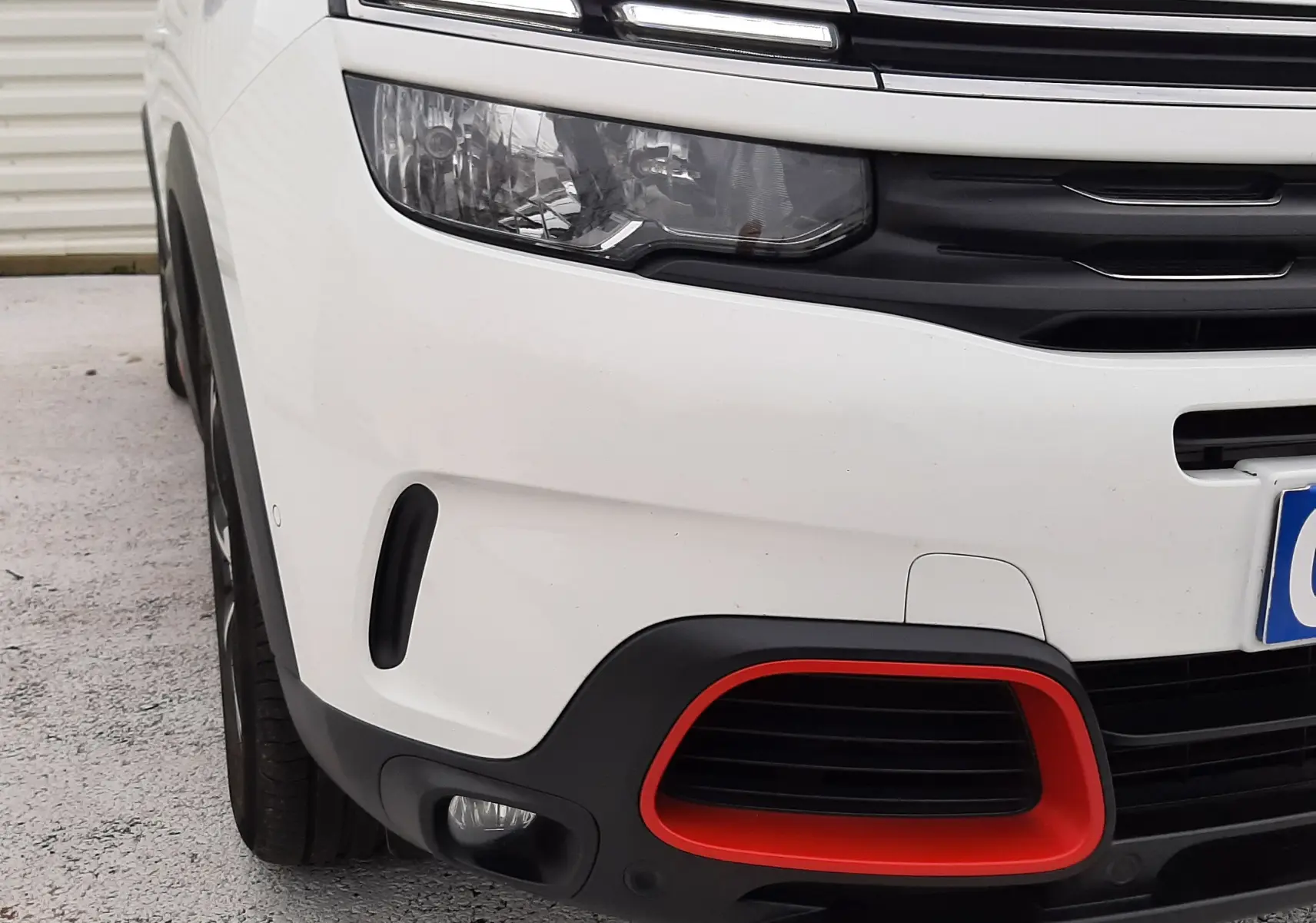 Gros plan sur l’avant gauche du Citroën C5 Aircross blanc de 2020, avec signature lumineuse LED et encadrement rouge du pare-chocs.