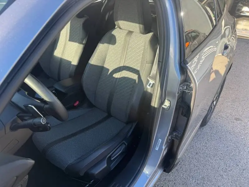 Vue intérieure côté conducteur du Peugeot 2008 Hybrid gris 2025, mettant en valeur le siège avant et la portière ouverte.