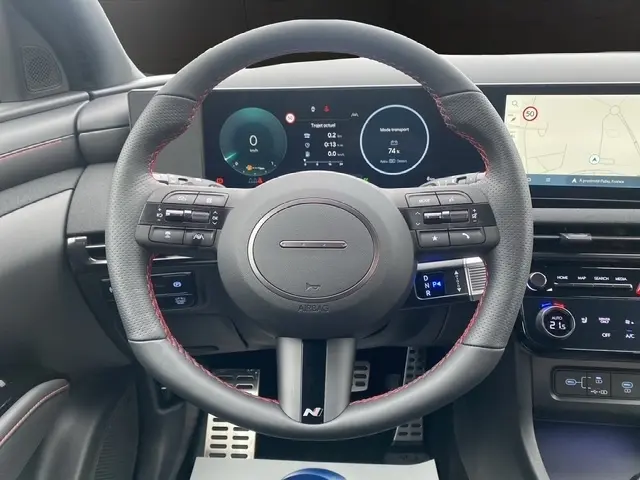 Vue centrée sur le volant cuir N Line avec coutures rouges du Hyundai Tucson gris foncé, tableau de bord digital et écran tactile.