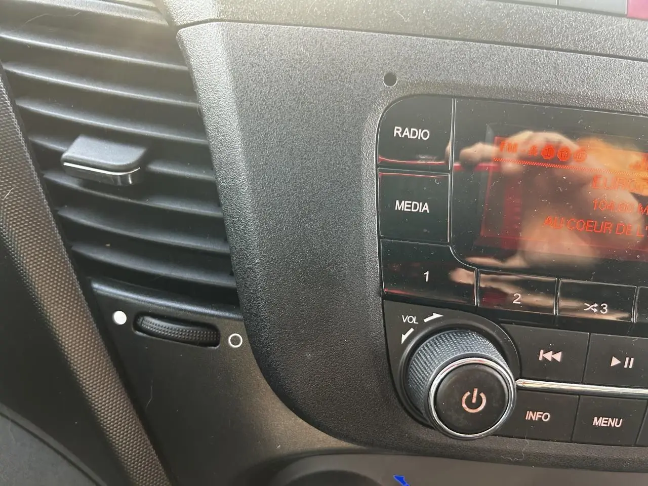 Gros plan sur la console centrale noire de l'IVECO Daily 2020, montrant les commandes radio et volume.