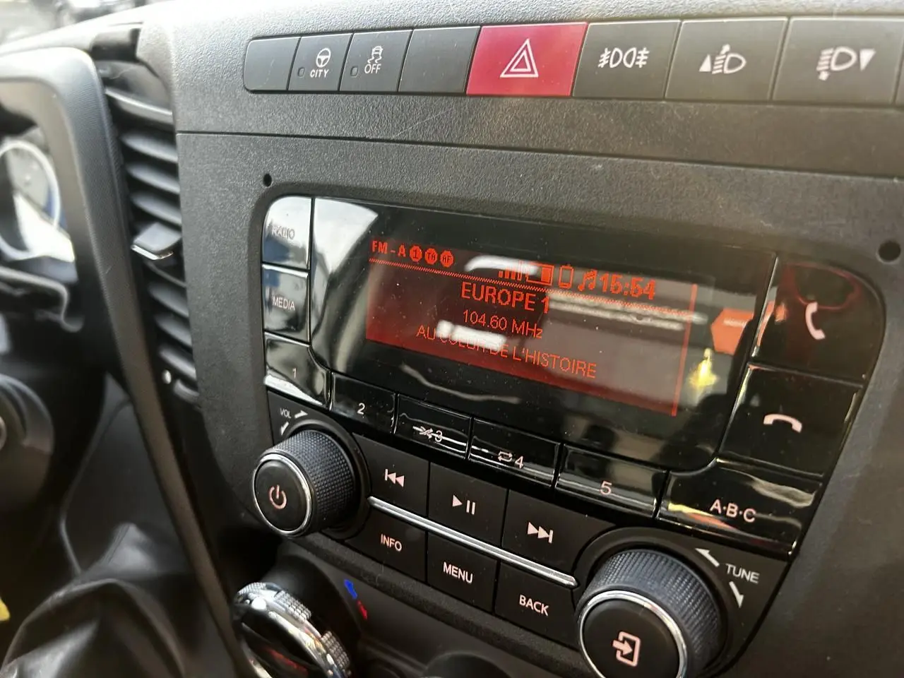 Gros plan sur la radio et les commandes centrales du tableau de bord de l'IVECO Daily blanc, affichant Europe 1 à 104,6 MHz.