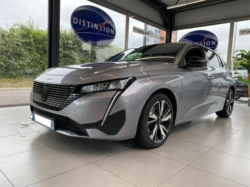 Vue 3/4 avant droit d'une Peugeot 308 gris Artense 2022 avec calandre noire et feux LED verticaux distinctifs.