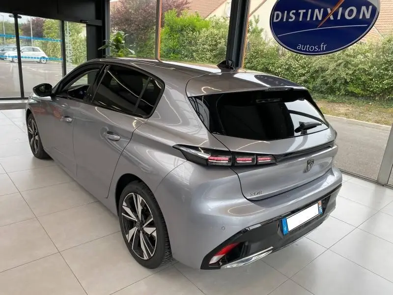 Vue 3/4 arrière droite d'une Peugeot 308 gris Artense 2022 avec feux LED et vitres teintées en showroom.