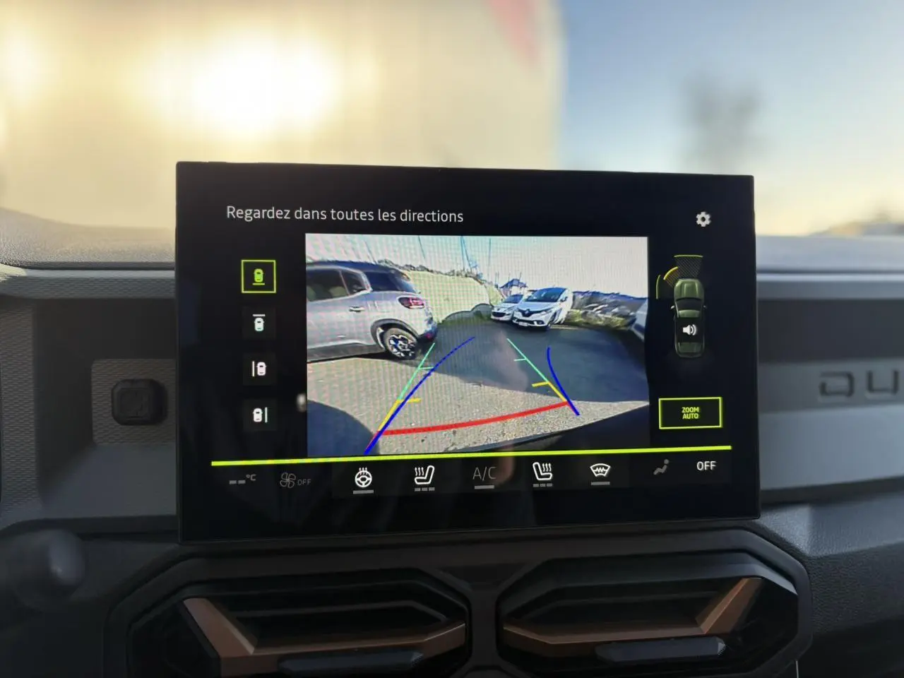 Écran tactile intérieur montrant la caméra 360° du Dacia Duster noir nacré, tableau de bord avec détails brun cuivré.