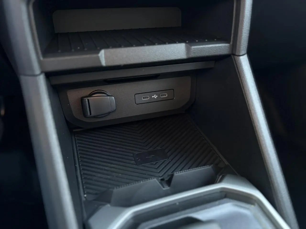 Détail de la console centrale du Dacia Duster 2026, zone de charge à induction avec ports USB et prise 12V.
