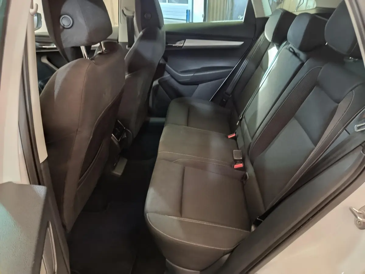 Vue intérieure côté droit montrant la banquette arrière noire du Skoda Karoq blanc 2024 avec sièges en tissu.