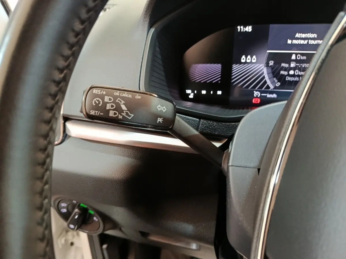 Gros plan sur la manette de commande du régulateur de vitesse et le combiné d'instruments numérique du Skoda Karoq blanc 2024.