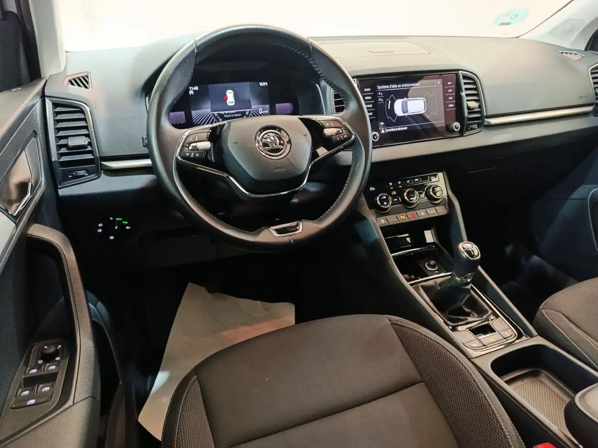 Intérieur noir du Skoda Karoq 2024 vu de face, avec volant cuir multifonctions et écran tactile central.