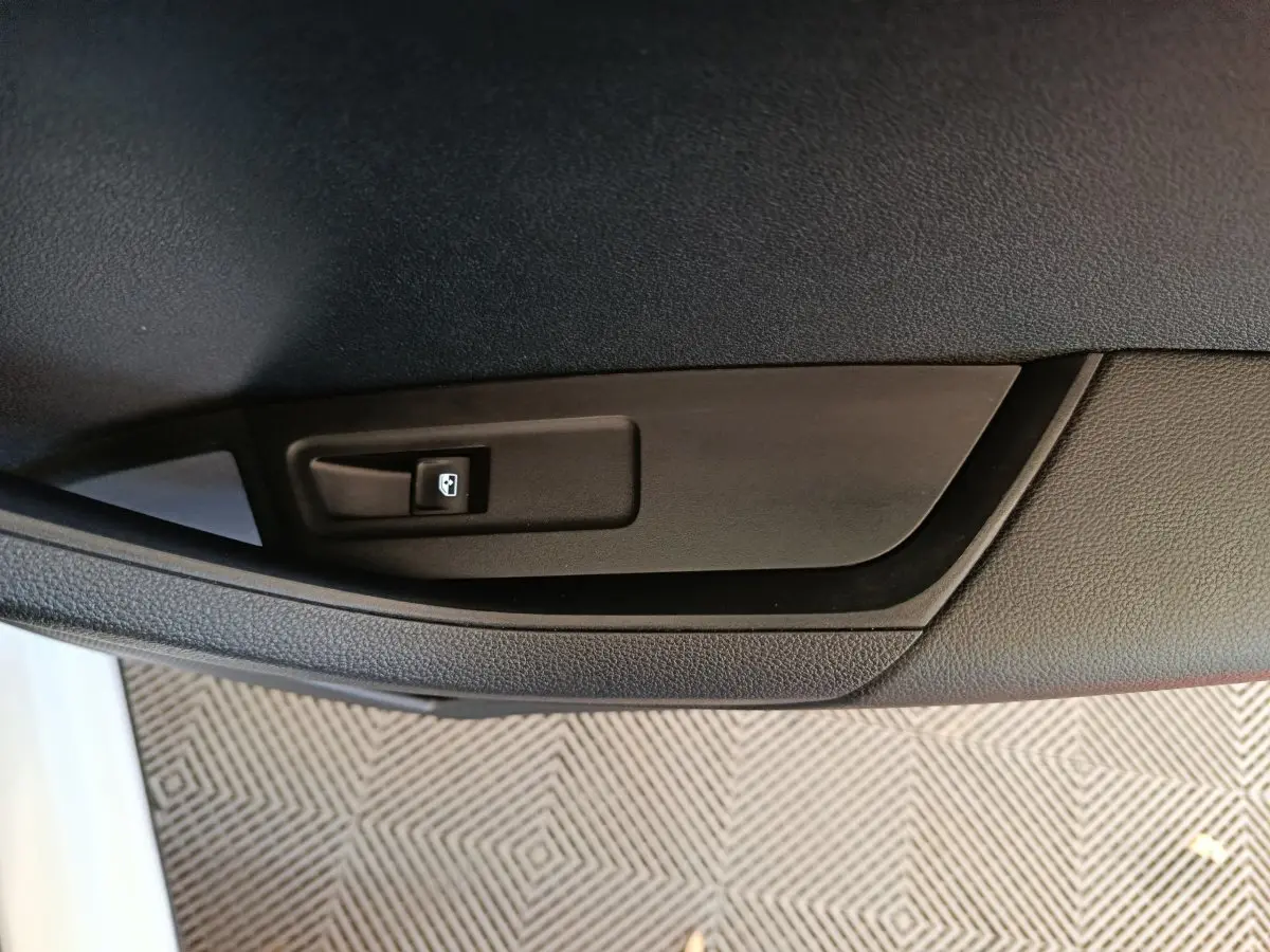 Bouton de commande de lève-vitre noir sur panneau de porte intérieur côté gauche d'un Skoda Karoq blanc.
