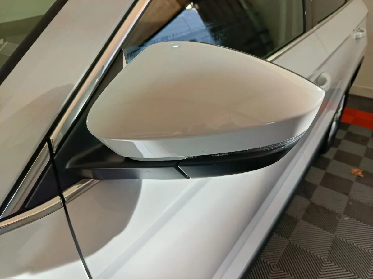 Rétroviseur côté gauche blanc du Skoda Karoq 2.0 TDI 116ch Selection 2024 avec clignotant intégré.