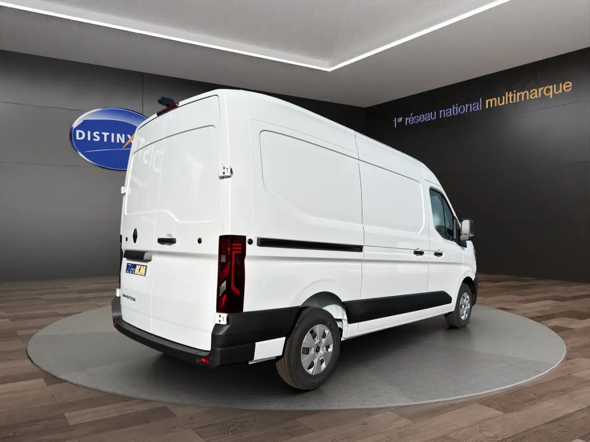 Vue 3/4 arrière droite du Renault Master blanc avec feux arrière LED et protections noires sur les bas de caisse.