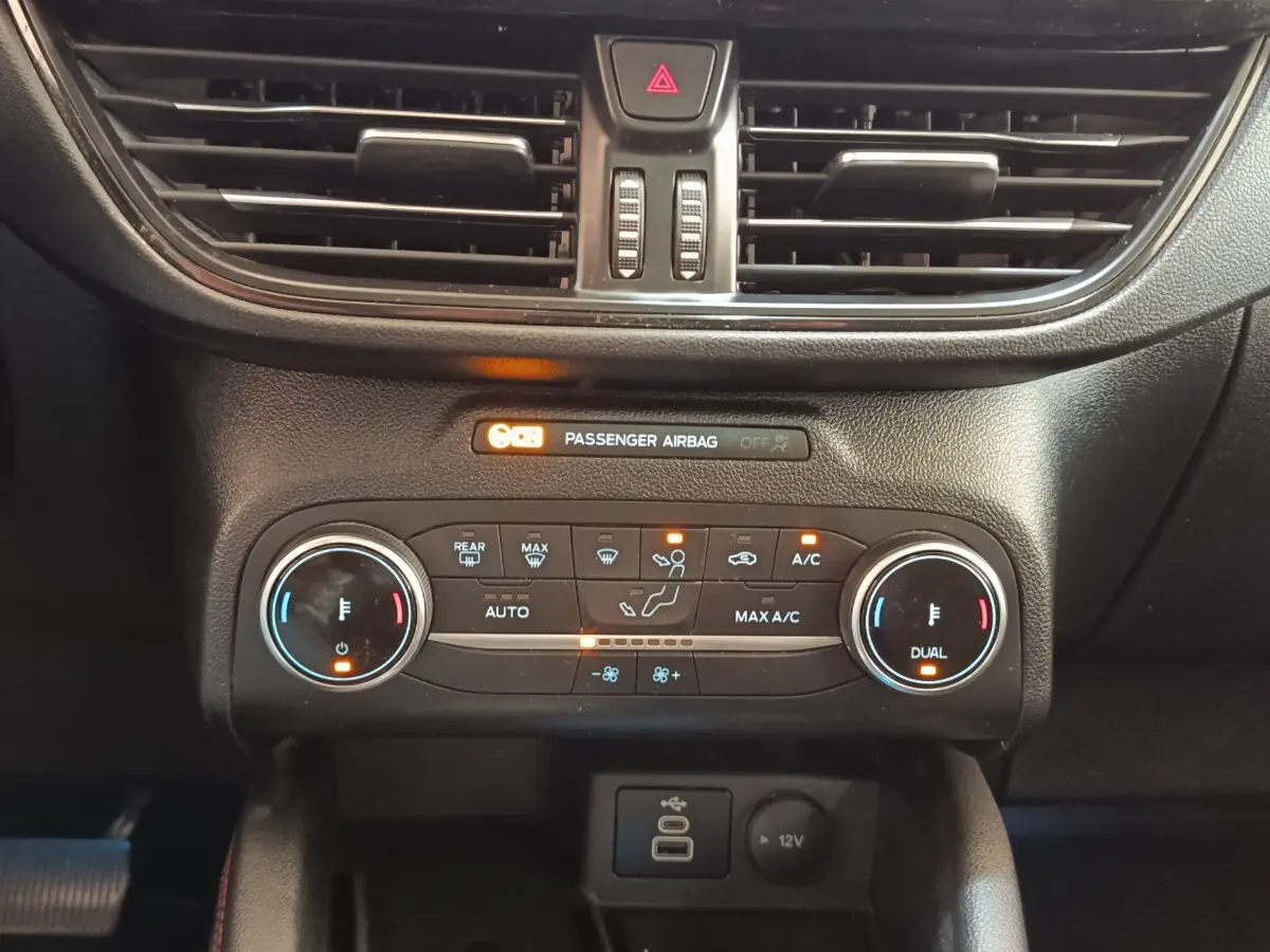 Vue rapprochée du tableau de bord central noir du Ford Kuga 2023, montrant la climatisation bi-zone et les commandes digitales.