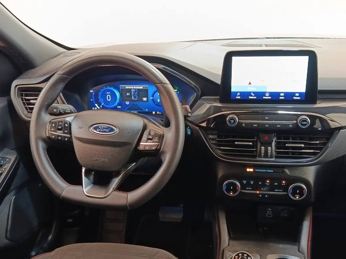 Vue intérieure frontale du tableau de bord du Ford Kuga gris foncé 2023 avec écran tactile central et volant multifonctions.