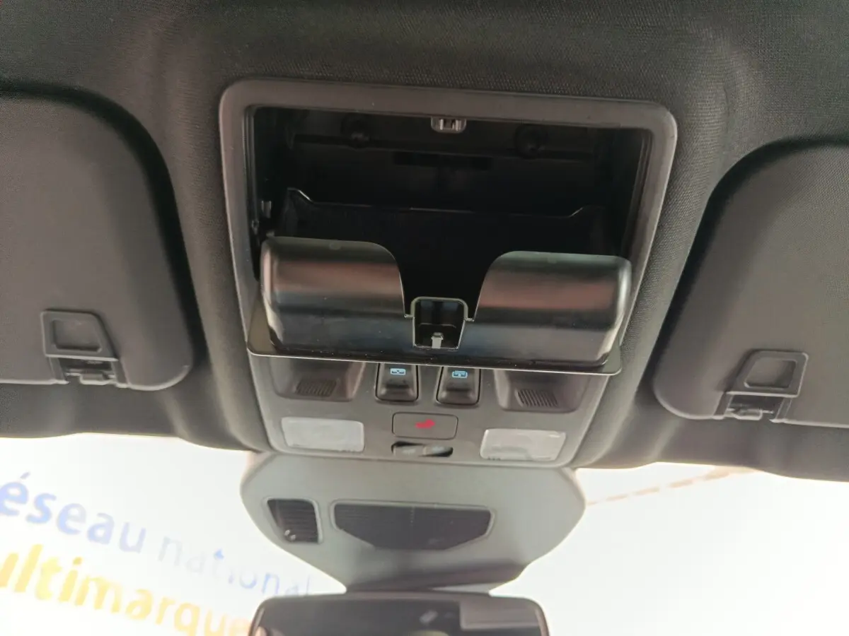 Vue intérieure du plafond de la Ford Kuga gris foncé 2023, montrant le compartiment lunettes et commandes lumineuses.