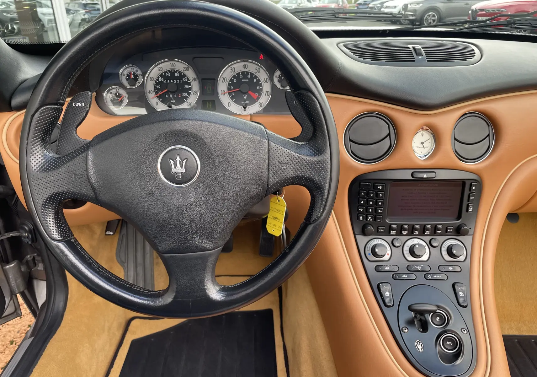Intérieur cuir camel de la Maserati Spyder 2002, vue du tableau de bord et volant noir avec commandes intégrées.