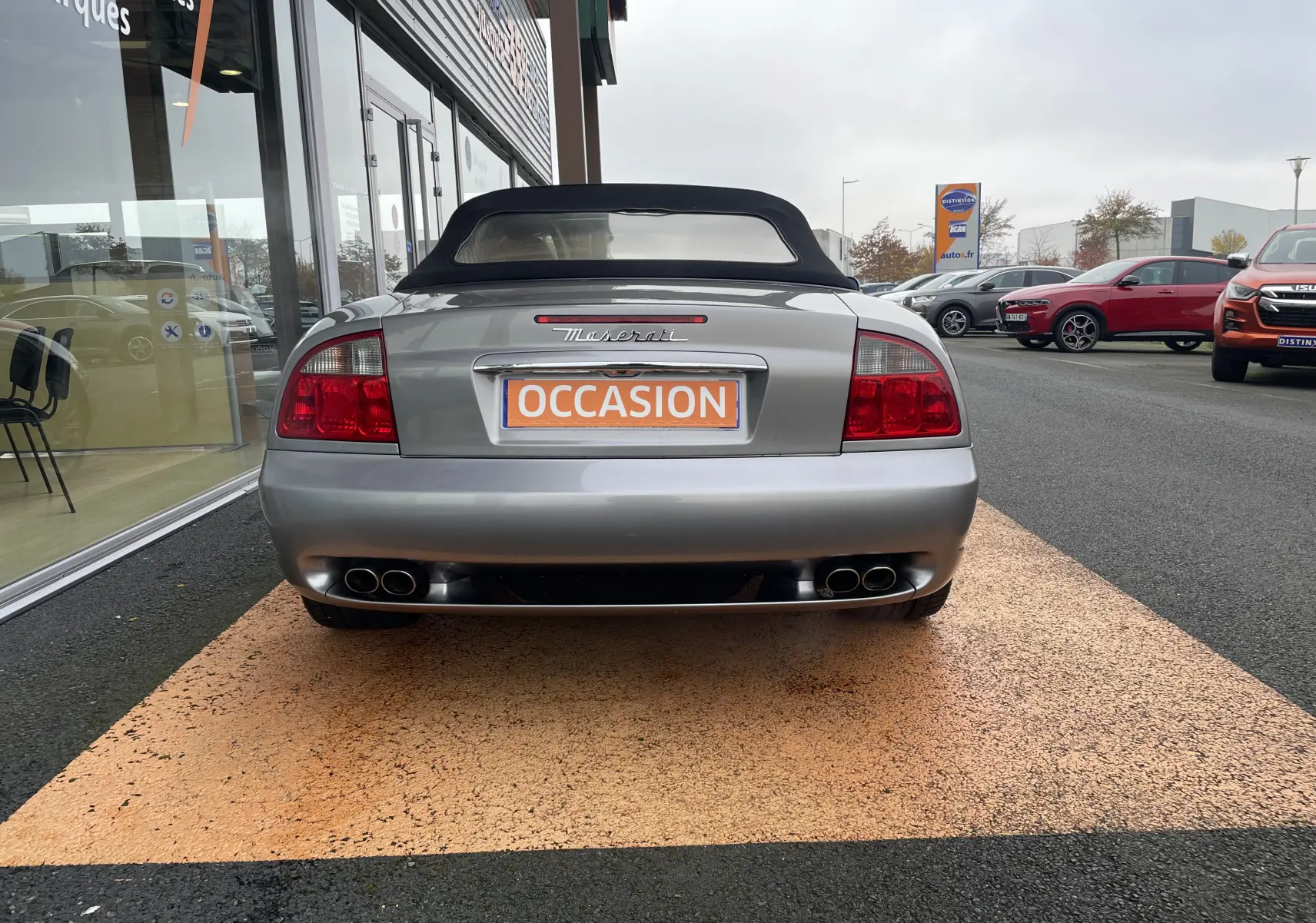 Vue arrière d'une Maserati Spyder gris Nuvolari de 2002 avec capote noire et double sortie d'échappement quadruple.
