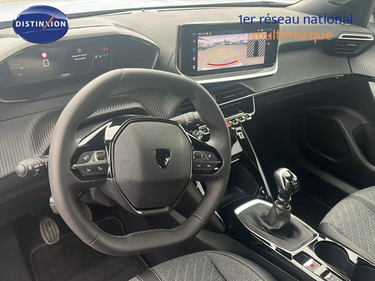Vue intérieure du poste de conduite du Peugeot 2008 blanc, avec volant compact, écran tactile et levier de vitesse manuel.