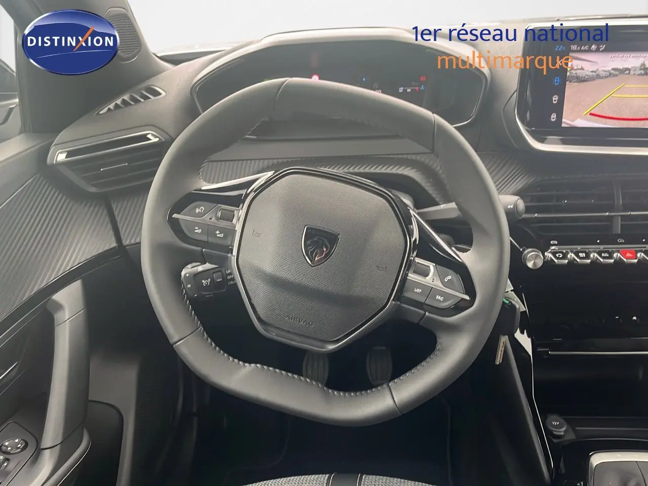 Vue centrée sur le volant cuir noir du Peugeot 2008 2025, avec tableau de bord digital et écran multimédia en arrière-plan.