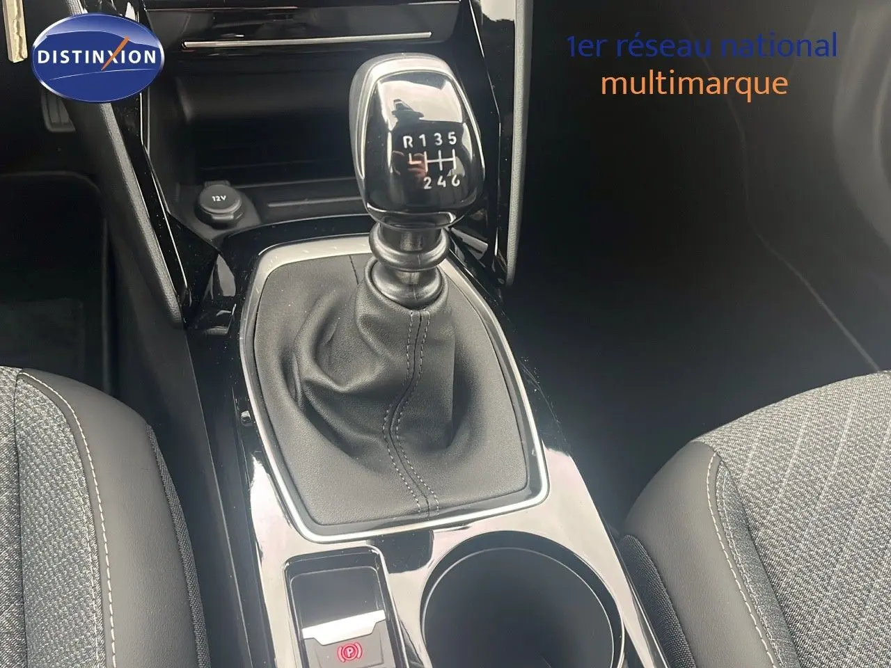 Le levier de vitesse manuel de la Peugeot 2008 blanc Okenite, entouré de sièges en tissu gris et cuir noir.