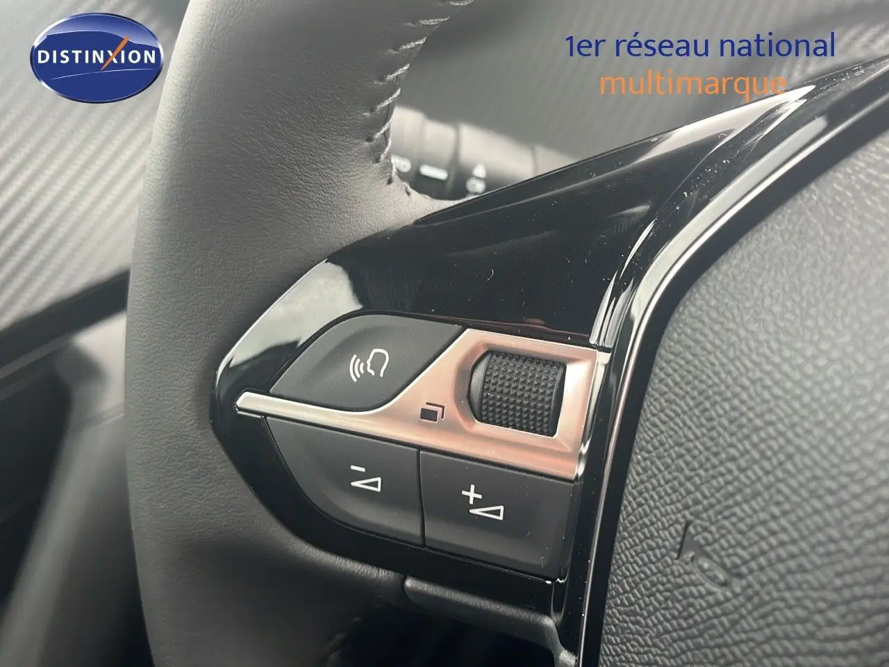 Gros plan sur les commandes de volume et téléphone du volant cuir noir d'une Peugeot 2008 blanche 2025.