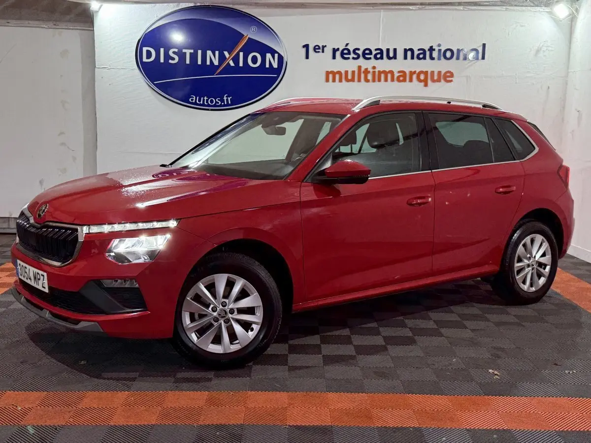 Vue latérale gauche d'un Skoda Kamiq rouge 2024 avec phares LED et jantes alliage en intérieur showroom.