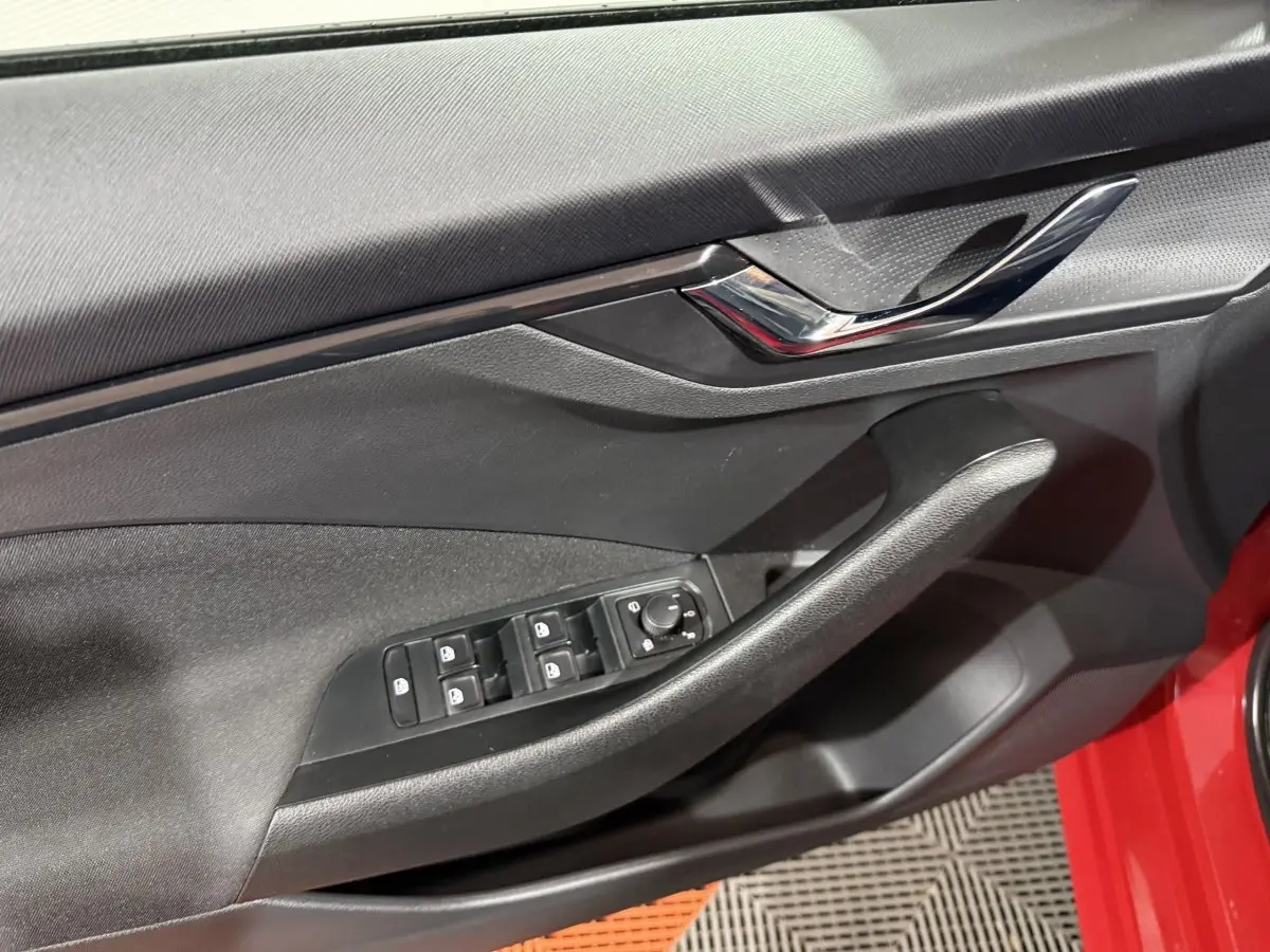 Gros plan sur la porte côté conducteur noire avec commandes électriques sur un Skoda Kamiq rouge 2024.