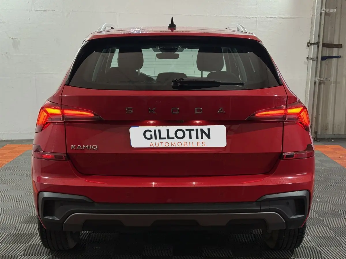 Vue arrière d'un Skoda Kamiq rouge 2024 avec feux LED allumés et logo visible sur un sol en damier.