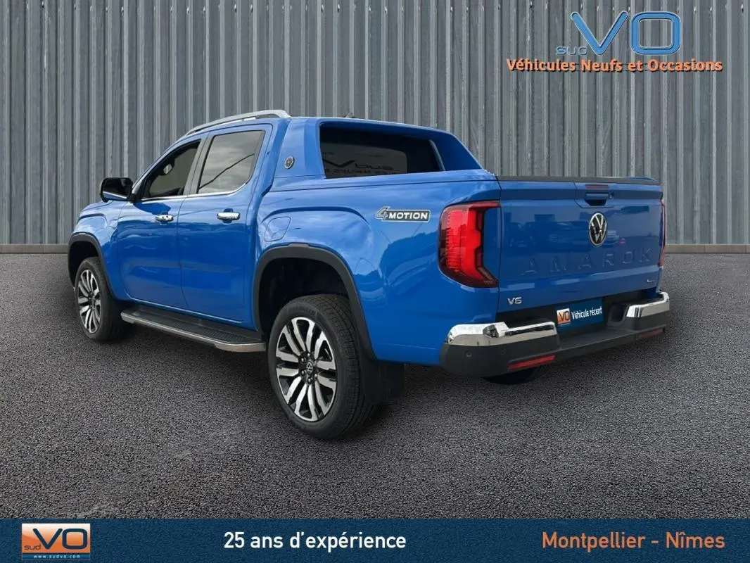 Vue 3/4 arrière droite d’un Volkswagen Amarok Aventura bleu avec jantes alliage 21 pouces et marchepieds visibles.