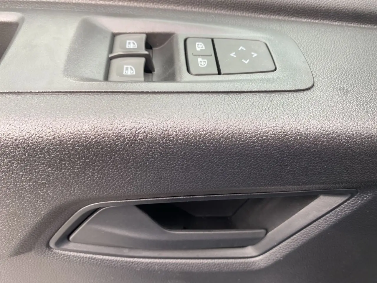 Gros plan sur la poignée intérieure et les commandes de vitres électriques côté conducteur du Renault Master blanc.