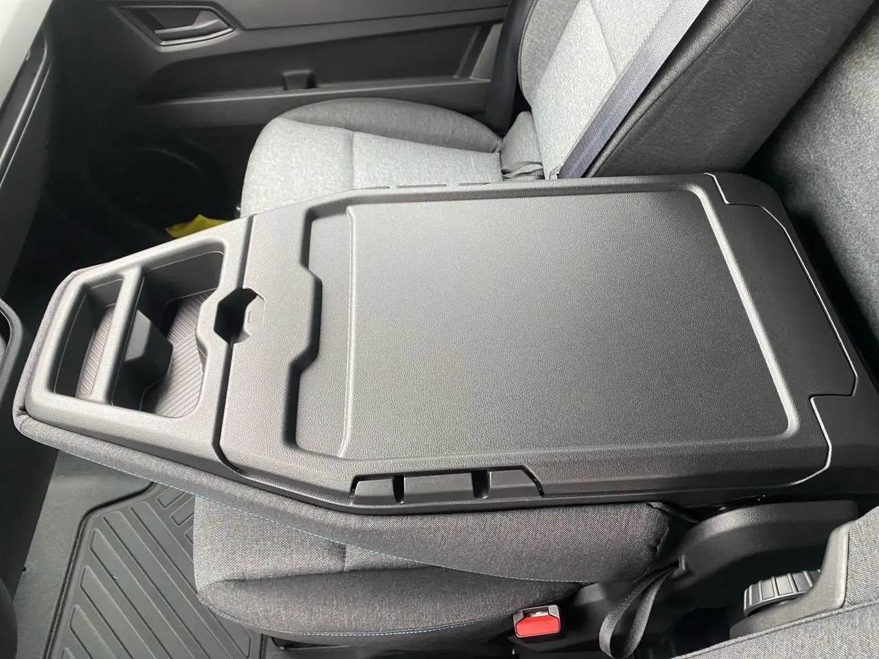 Vue rapprochée de la banquette passager grise avec bureau mobile intégré dans un Renault Master blanc 2025.