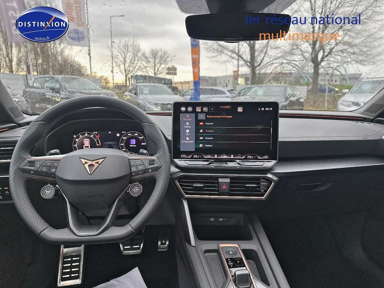 Intérieur de la CUPRA Leon ST 2025 vu de face, volant cuir sport et écran tactile central allumé.