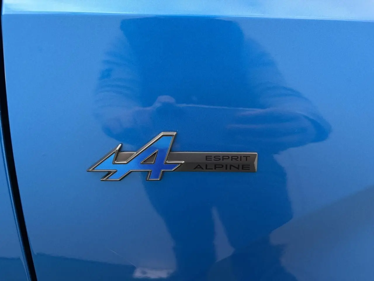 Gros plan sur le badge Esprit Alpine bleu et noir sur la carrosserie Summit Blue d'une Renault Rafale 2025.