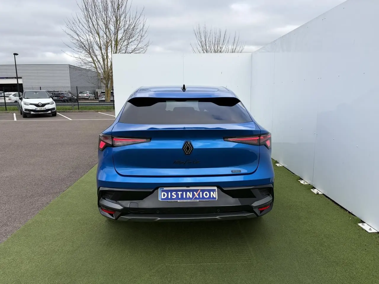 Vue arrière d'une Renault Rafale Summit Blue 2025 avec feux LED fins et logo noir central sur fond bleu.