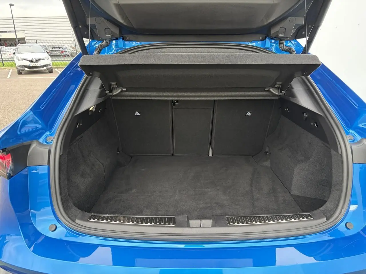 Coffre ouvert vu de l'arrière d'une Renault Rafale Summit Blue, montrant l'espace de chargement vide et les finitions intérieures noires.