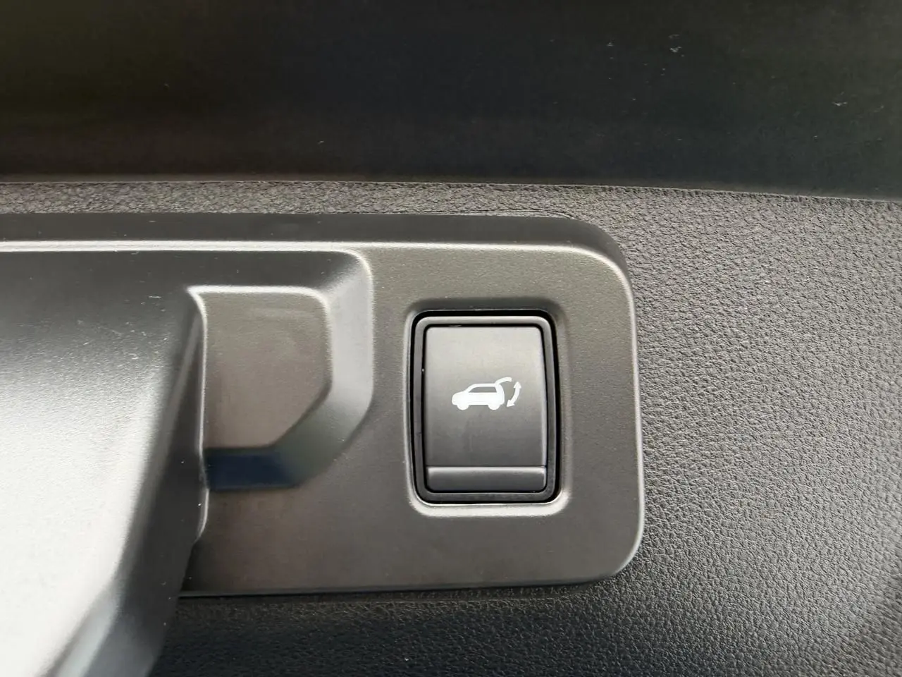 Bouton intérieur noir avec symbole d'ouverture de hayon sur Renault Rafale 2025, détail de commande.