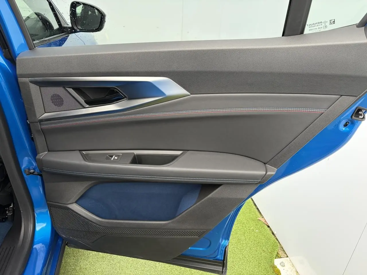 Vue intérieure côté gauche de la porte avant d'une Renault Rafale Summit Blue avec surpiqûres tricolores et insert textile bleu.