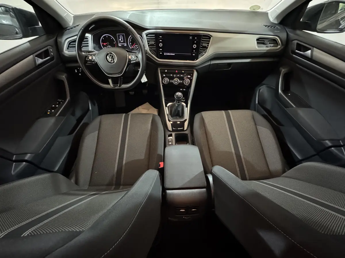 Intérieur du Volkswagen T-Roc 2021, vue avant centrée sur tableau de bord et sièges tissu gris foncé.