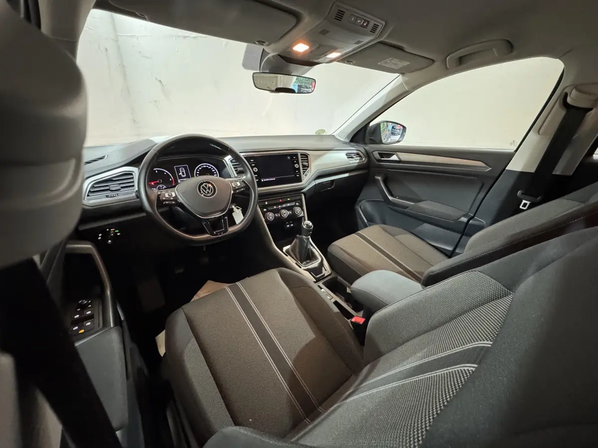 Intérieur du Volkswagen T-Roc 2021 en vue côté conducteur, montrant tableau de bord et sièges gris foncé.