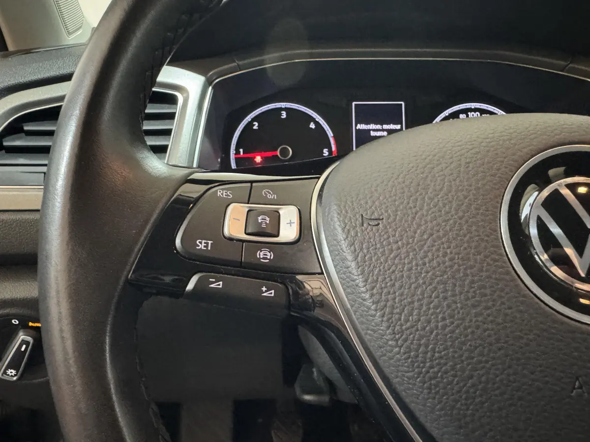 Gros plan sur le volant cuir noir du Volkswagen T-Roc 2021 avec commandes multifonctions et tableau de bord numérique.