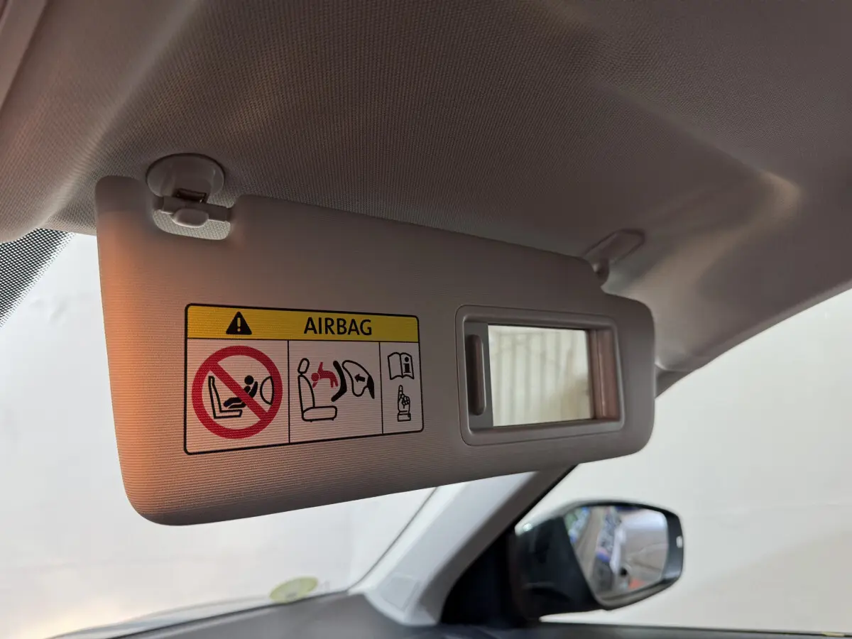 Détail du pare-soleil côté conducteur avec miroir et avertissement airbag dans un Volkswagen T-Roc gris foncé.