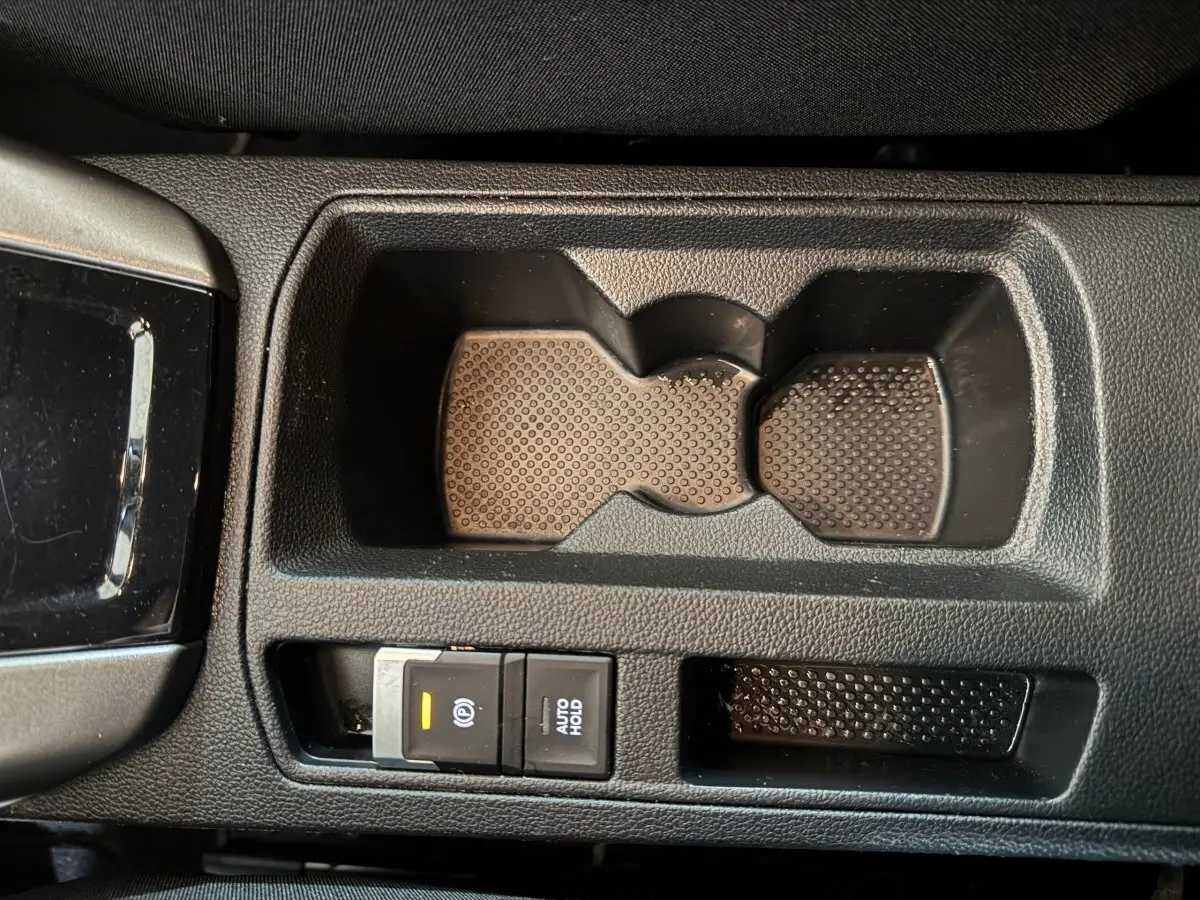 Gros plan sur la console centrale noire du Volkswagen T-Roc 2021, montrant le frein à main électrique et porte-gobelets.