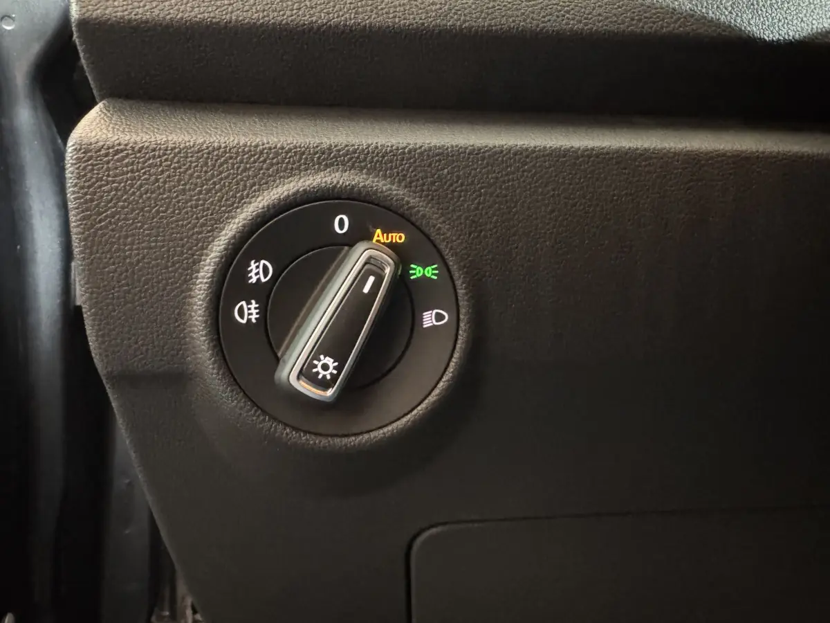 Gros plan sur le bouton de commande des phares du Volkswagen T-Roc gris foncé, avec réglage sur automatique.