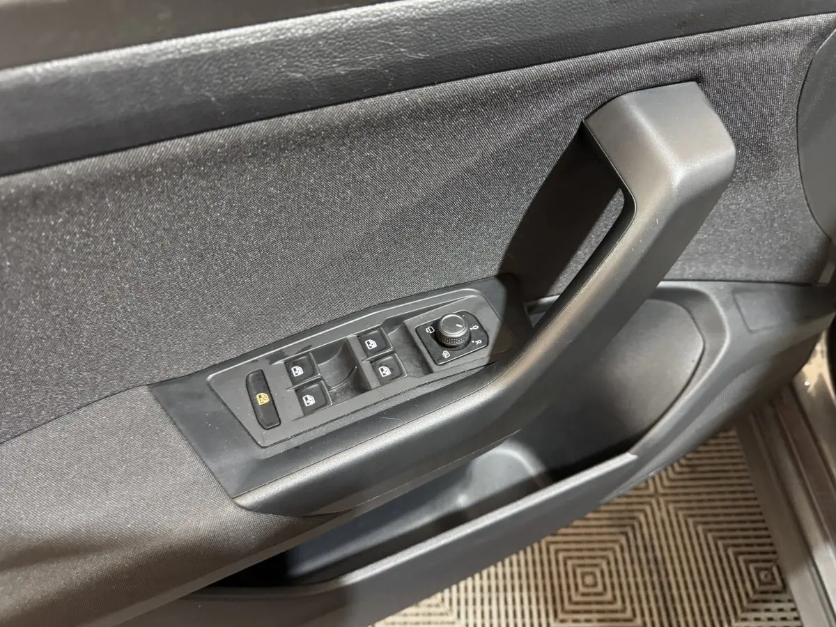 Panneau de porte côté conducteur du Volkswagen T-Roc gris foncé, avec commandes électriques des vitres et rétroviseurs.