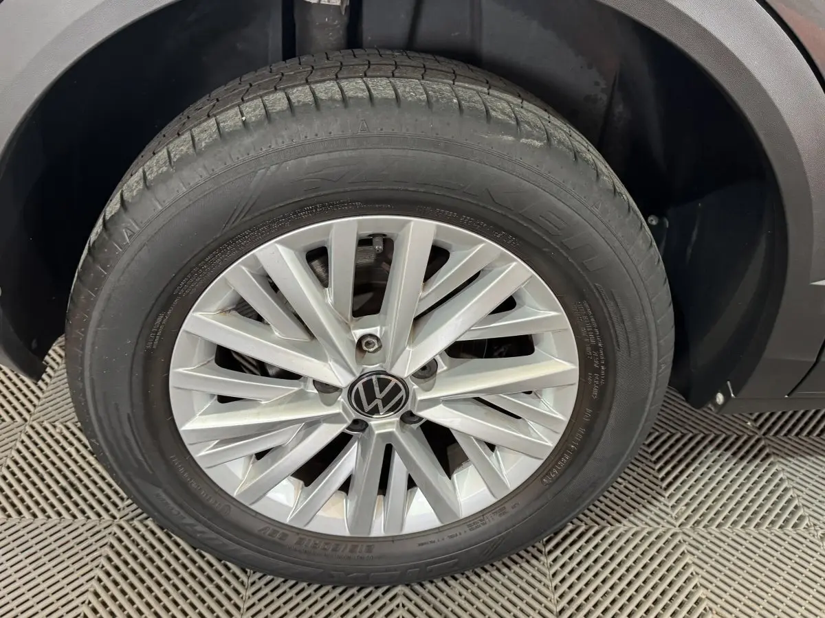 Gros plan sur la roue avant droite avec jante alliage argentée du Volkswagen T-Roc gris foncé.