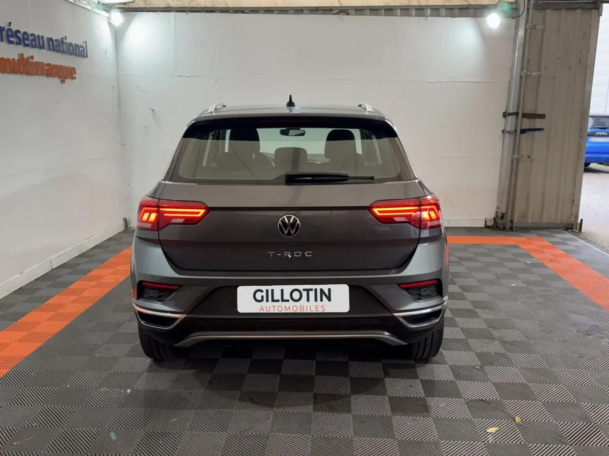 Vue arrière d'un Volkswagen T-Roc gris foncé 2021 avec feux LED allumés dans un garage.