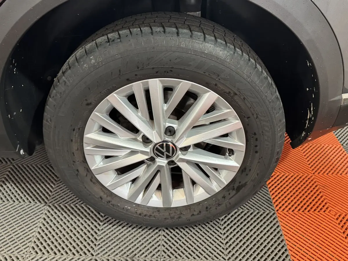 Gros plan sur la roue avant droite du Volkswagen T-Roc gris foncé avec jante alliage et logo VW au centre