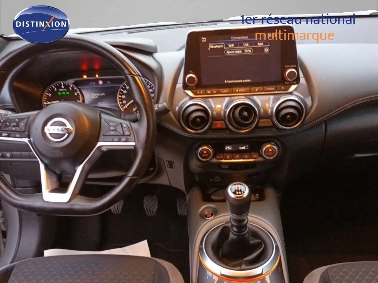 Intérieur du Nissan Juke 2020 gris platine, vue de face sur le tableau de bord avec écran tactile et levier de vitesse manuel.