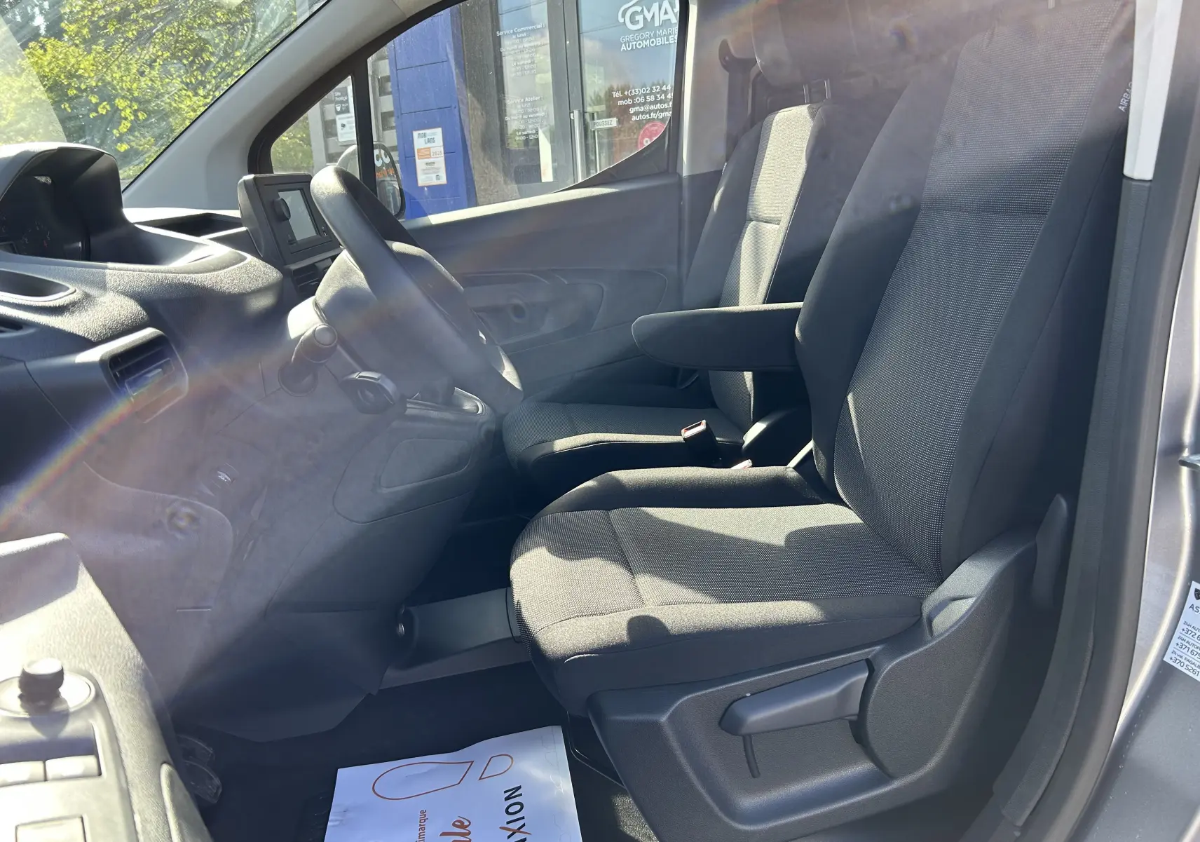 Vue intérieure côté gauche du poste de conduite du DANGEL Partner 4x4 gris Artense, montrant sièges tissu et tableau de bord.