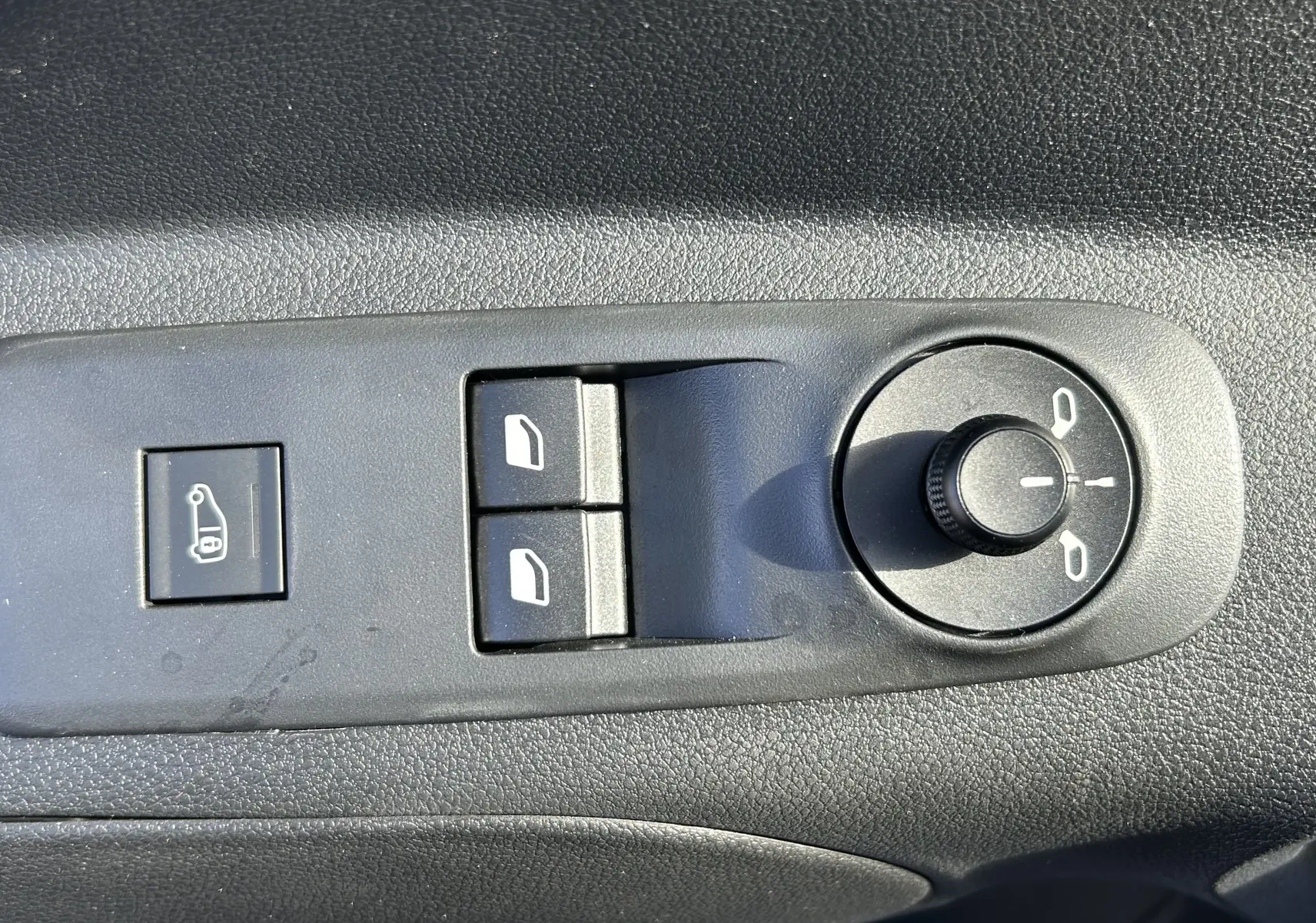 Gros plan sur les commandes de réglage des rétroviseurs et des vitres côté conducteur du DANGEL Peugeot Partner gris Artense.