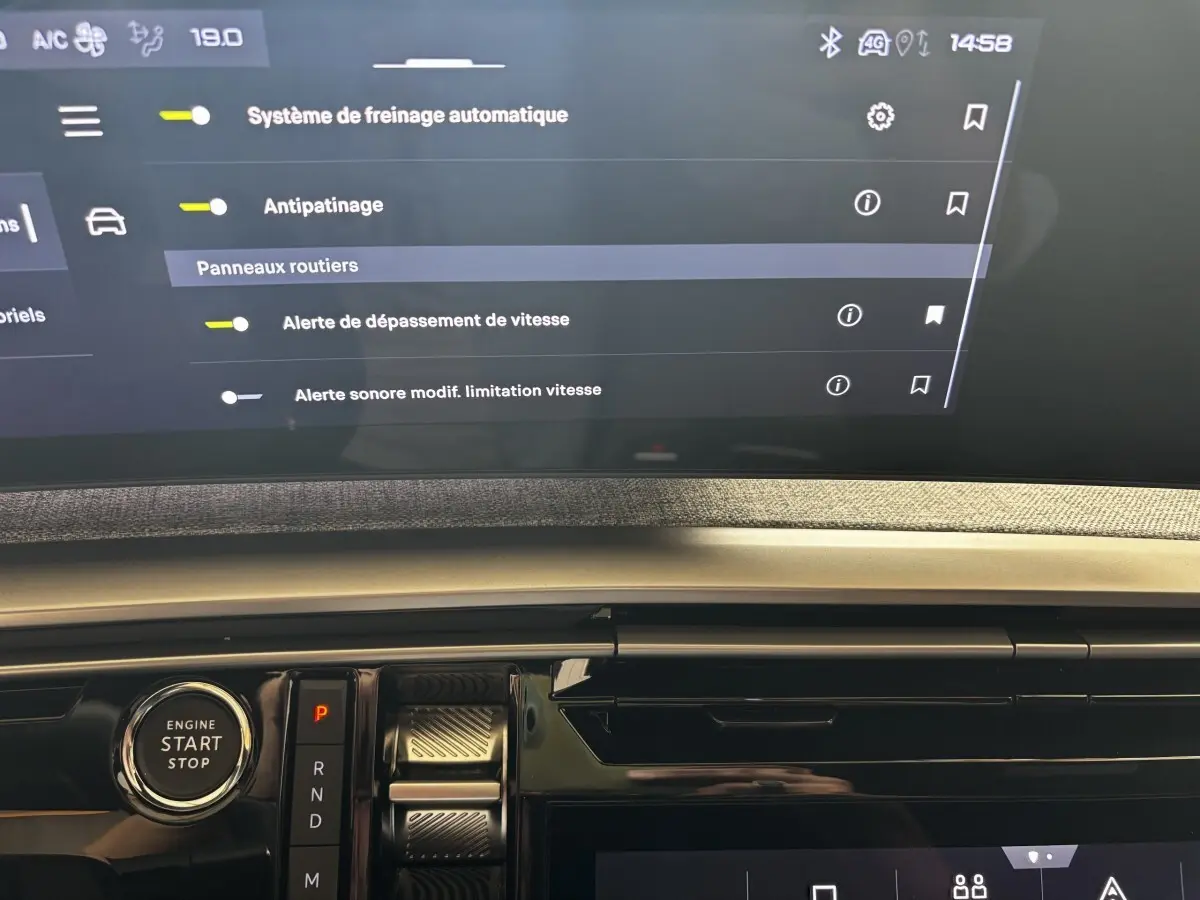 Détail intérieur du tableau de bord Peugeot 3008 gris clair avec bouton démarrage et écran tactile affichant les aides à la conduite.
